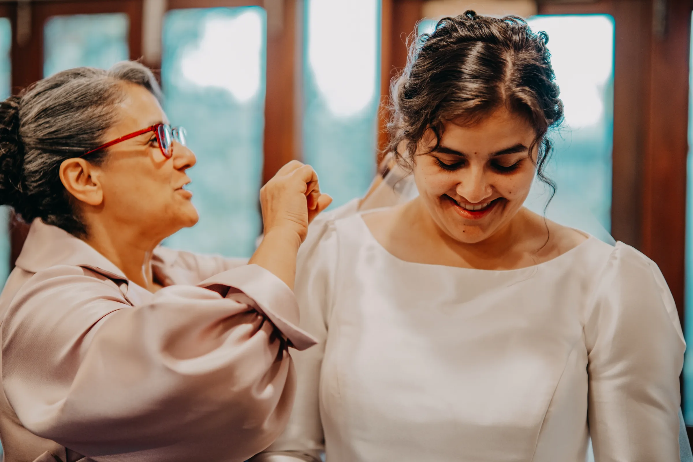 Cassandra's mother fastening her earring during bridal preparations at the Farm Boudoir, Chapel Farm Estate