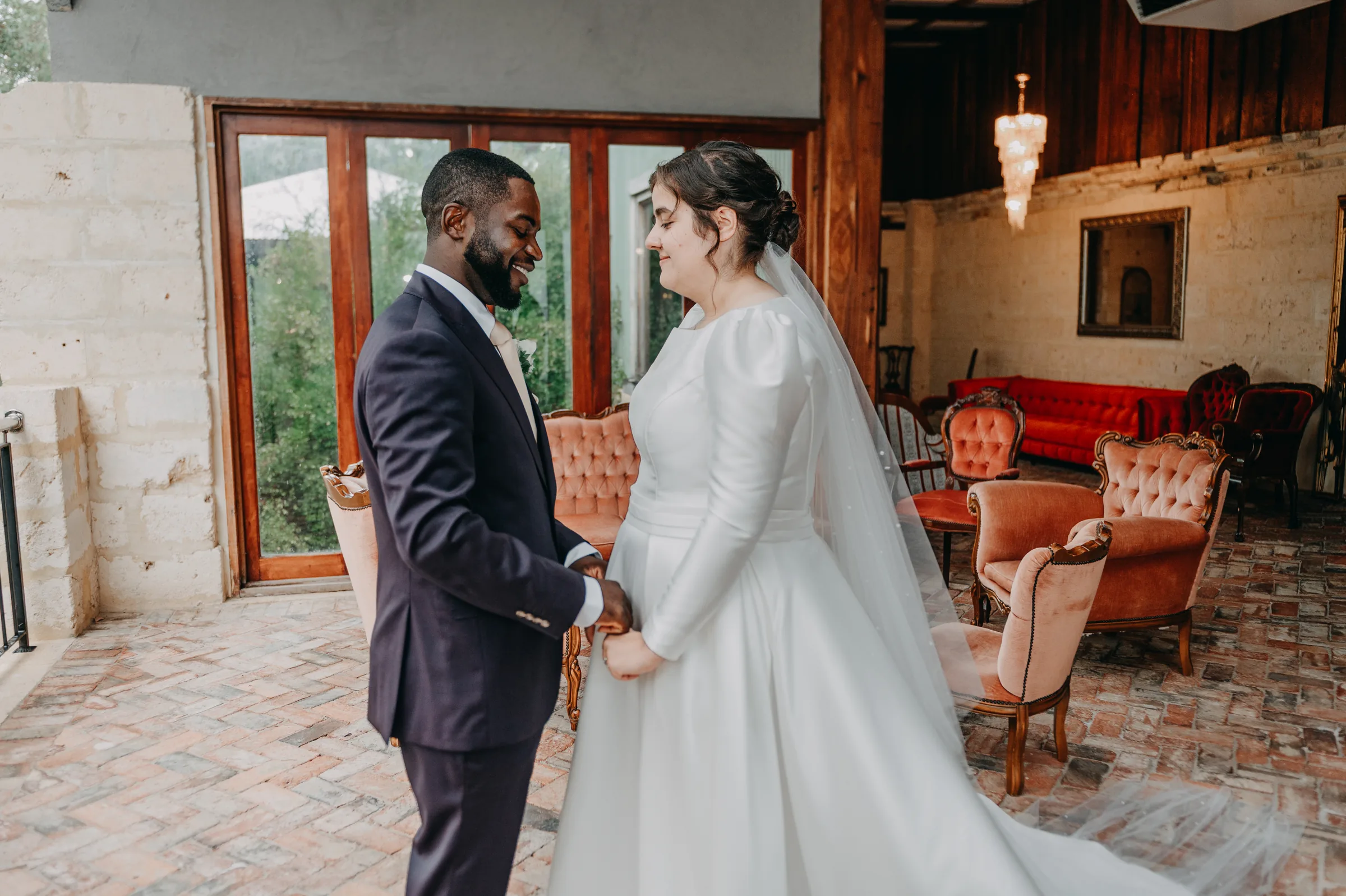 Cassandra and Jonathan holding hands in the rustic stone-walled room at Chapel Farm Estate before their vows