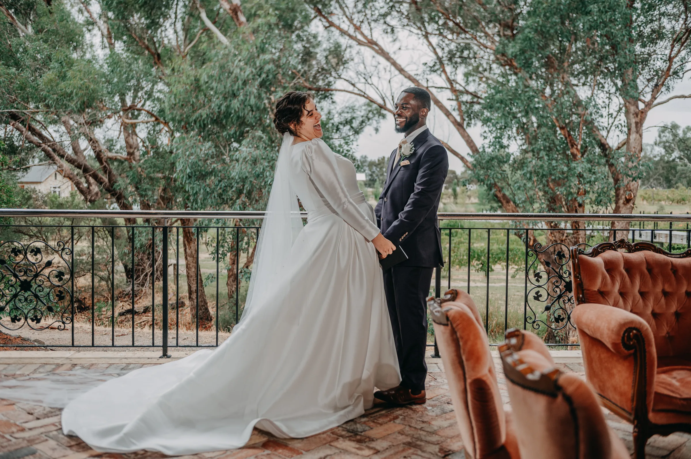Cassandra walking through Chapel Farm Estate in her wedding gown with Jonathan following behind