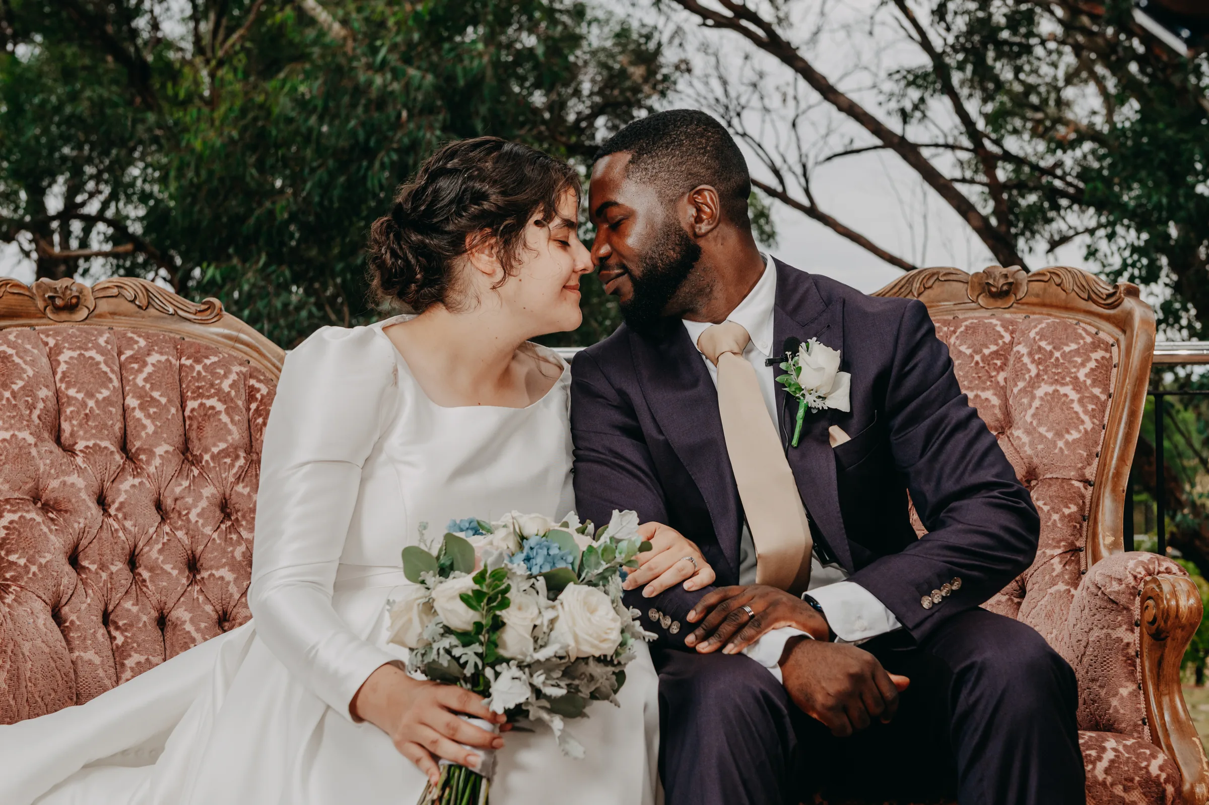 Cassandra and Jonathan laughing together on a vintage couch during portraits at Chapel Farm Estate