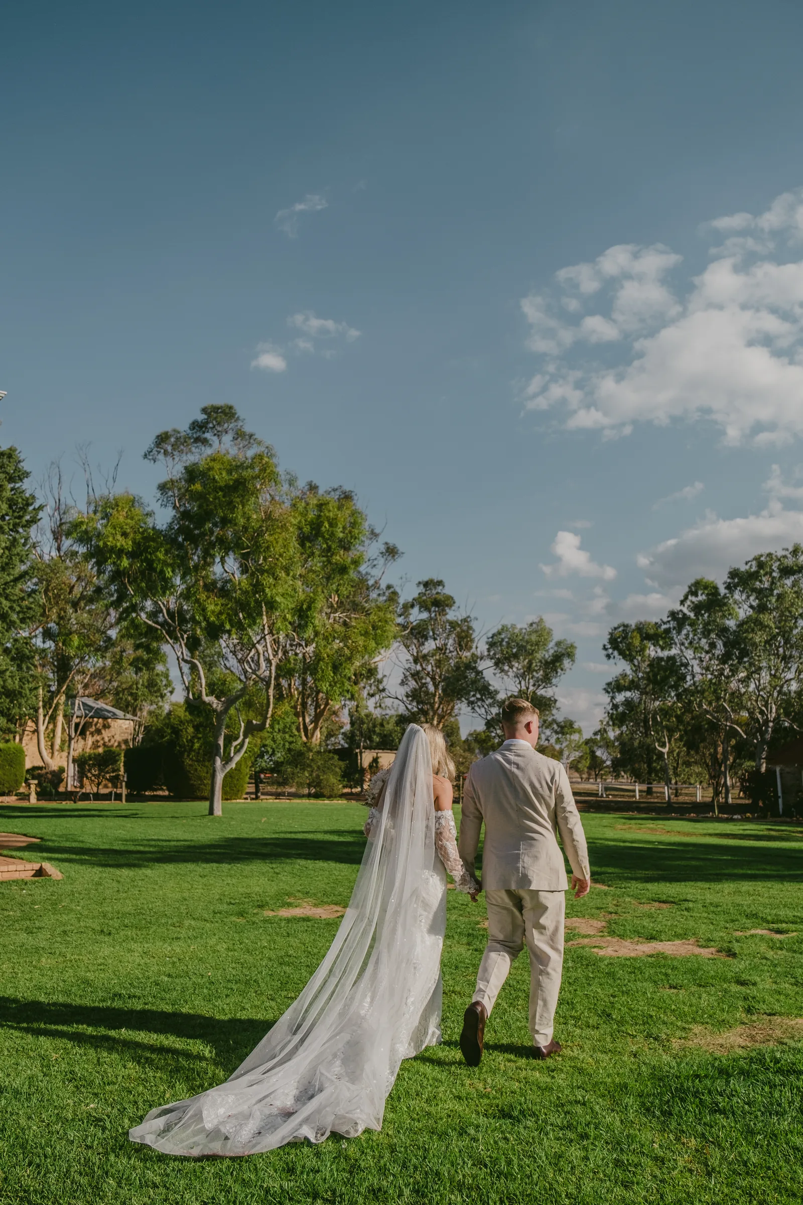 Grace walking across the lawn at Buckland Estate, her veil trailing behind her in the breeze