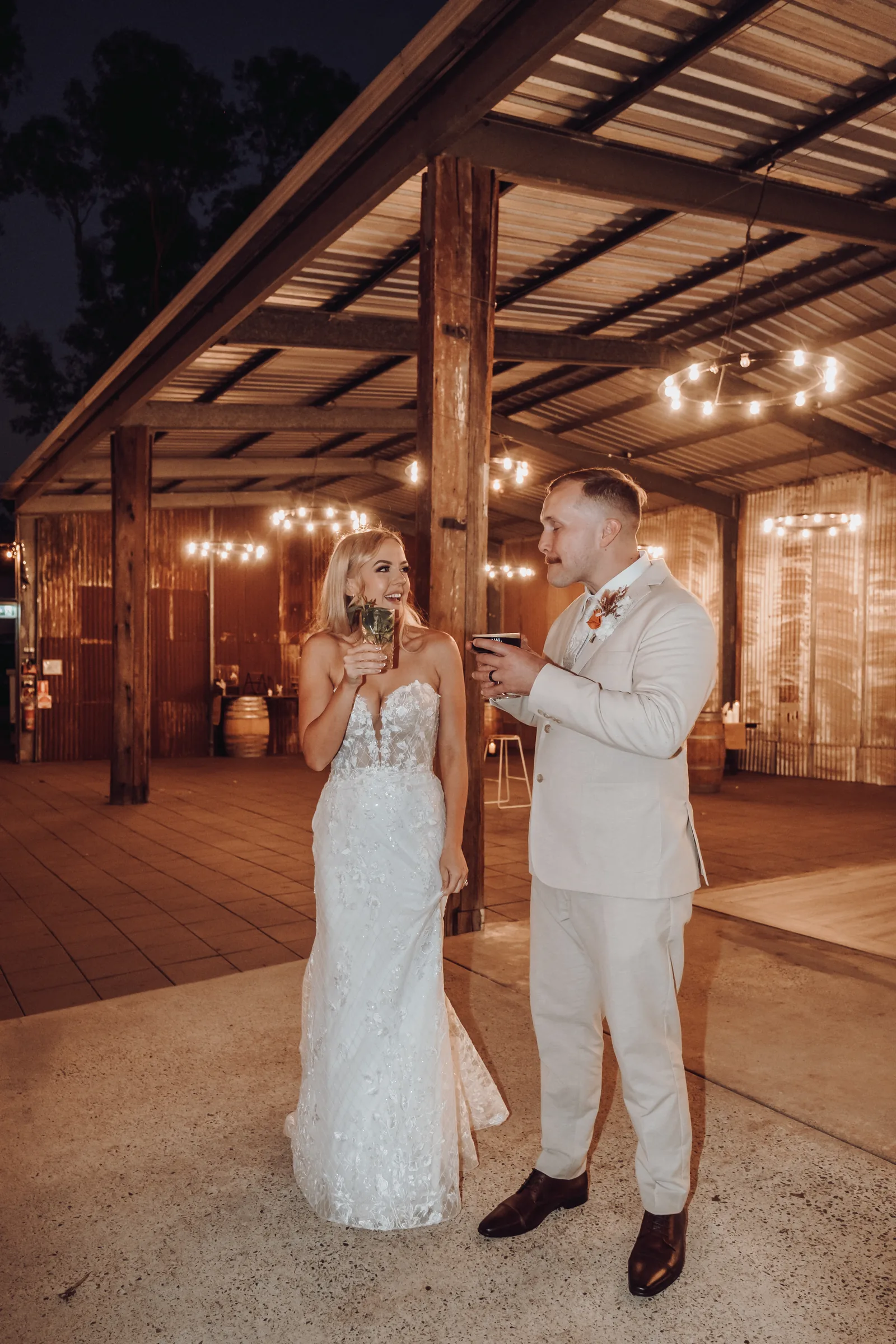 Grace and Lachie sharing their first dance under a timber pergola strung with fairy lights at Buckland Estate