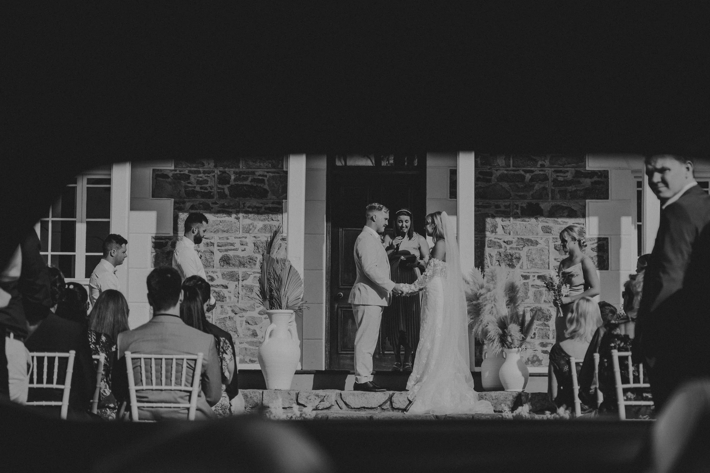 Black and white wide shot of Grace and Lachie's ceremony on the lawn in front of Buckland Estate