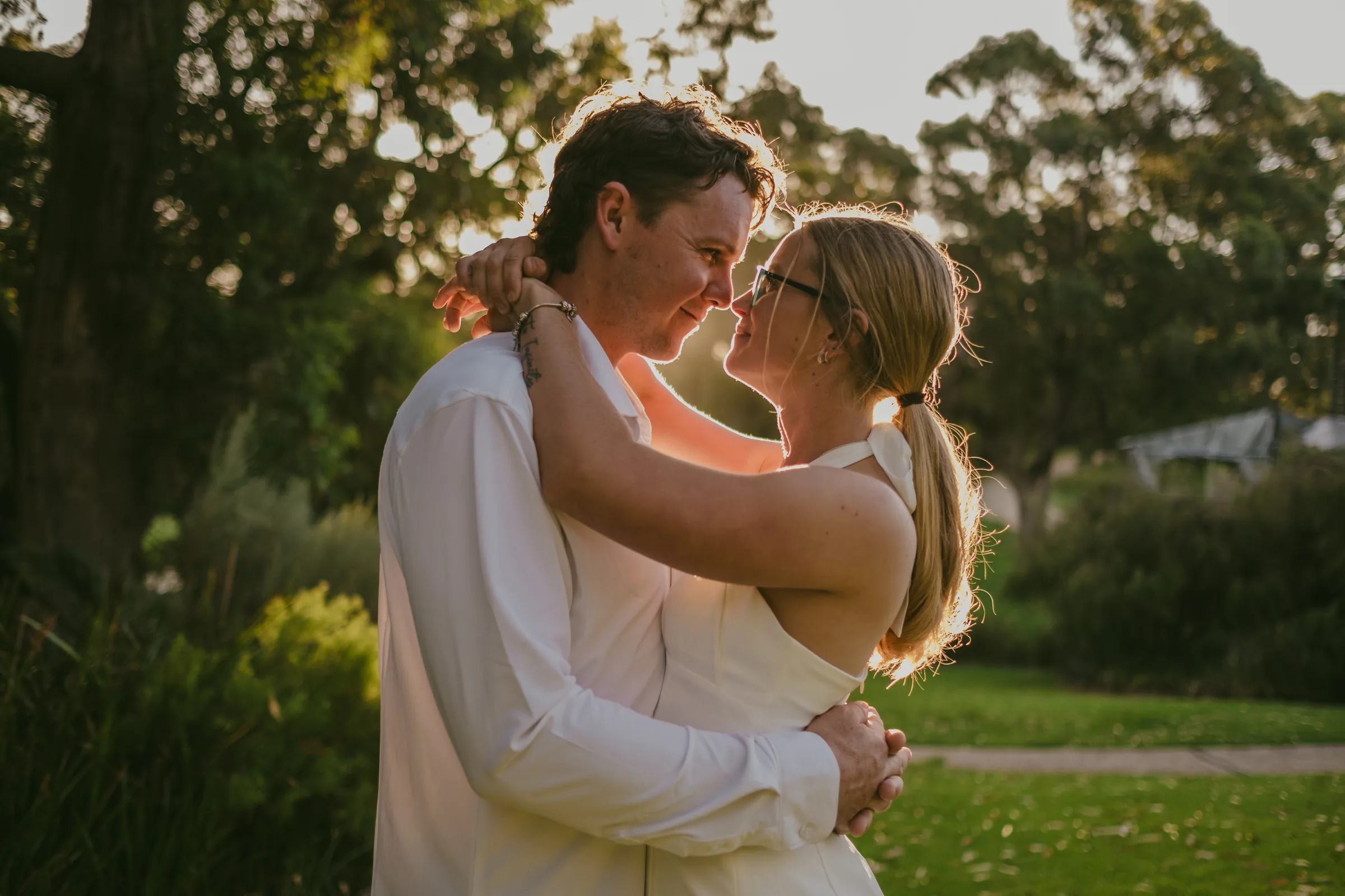 Kayla and Brett embracing under golden backlight through the trees at Kings Park