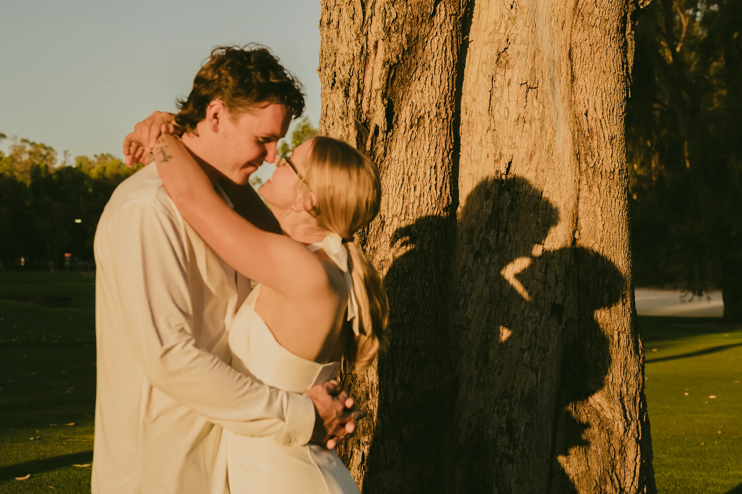 Kayla and Brett with foreheads together beneath the trees at Kings Park as the light fades