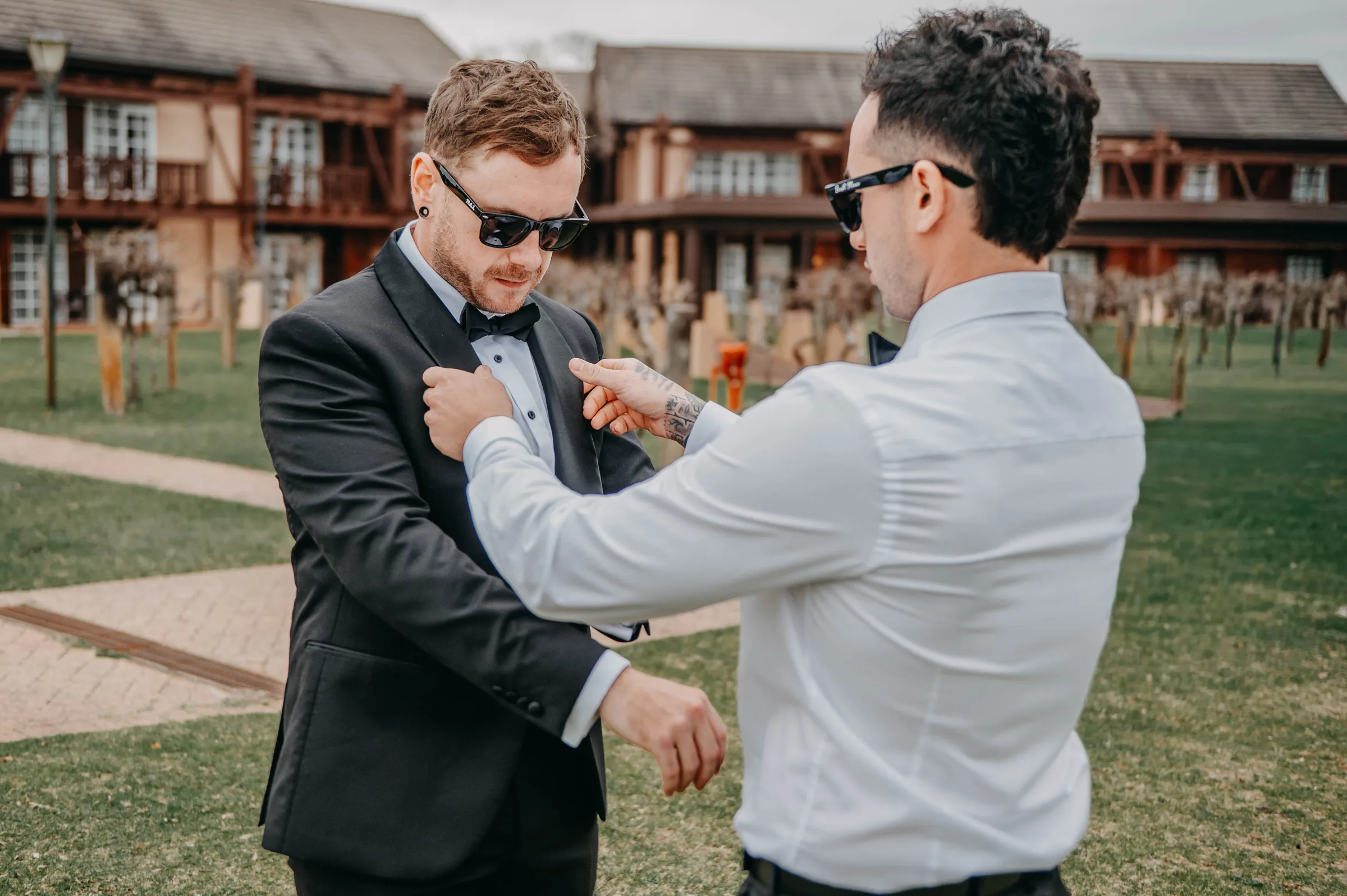 Mitch and a groomsman in sunglasses adjusting jackets on The Vines Resort grounds