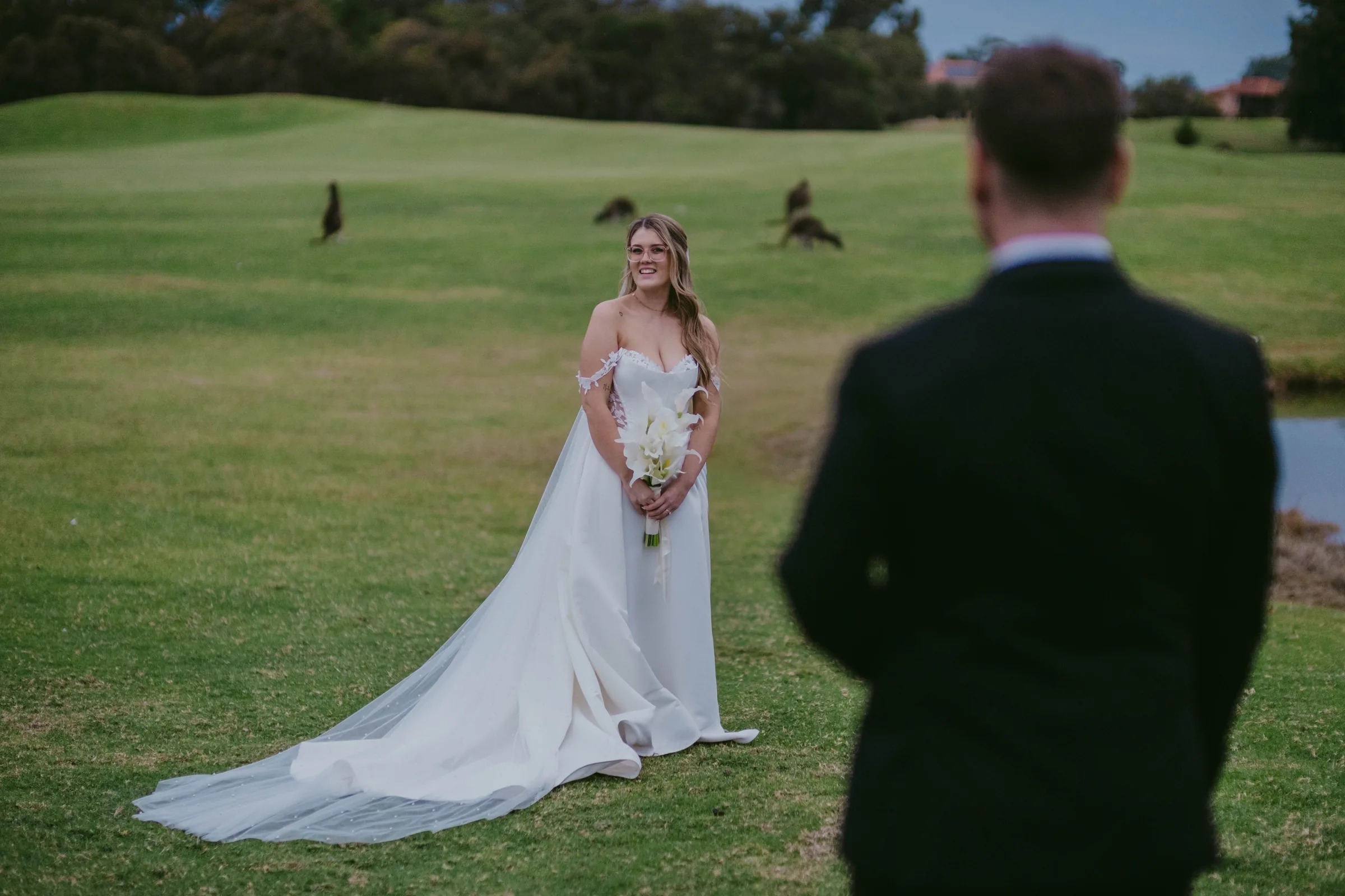 Wide shot of Kirra walking away across The Vines Resort fairway in her wedding gown