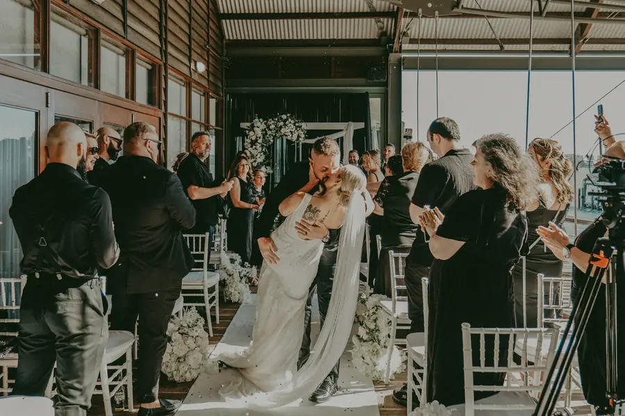 Black and white candid of Chantelle and Zach kissing as guests walk past, Perth CBD wedding