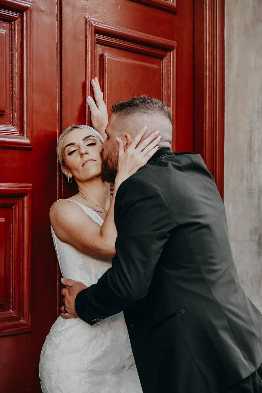 Chantelle and Zach sharing an intimate moment against a red door near Supreme Court Gardens, Perth