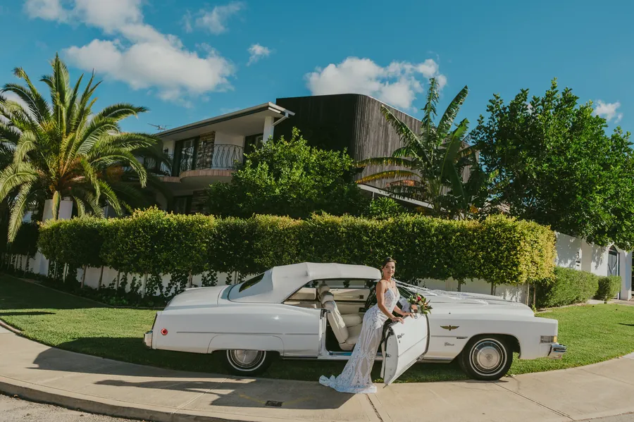 Katia and Sean kissing as their bridal party cheers with hands raised at sunset