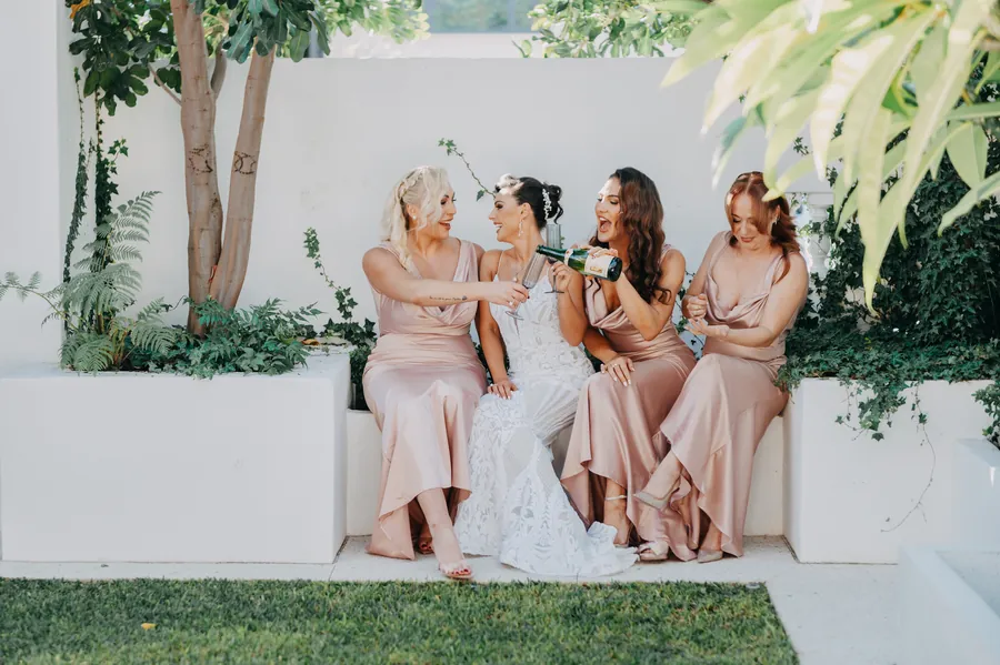Black and white portrait of the bridal party gathered on the vintage Cadillac, shipping containers in the background