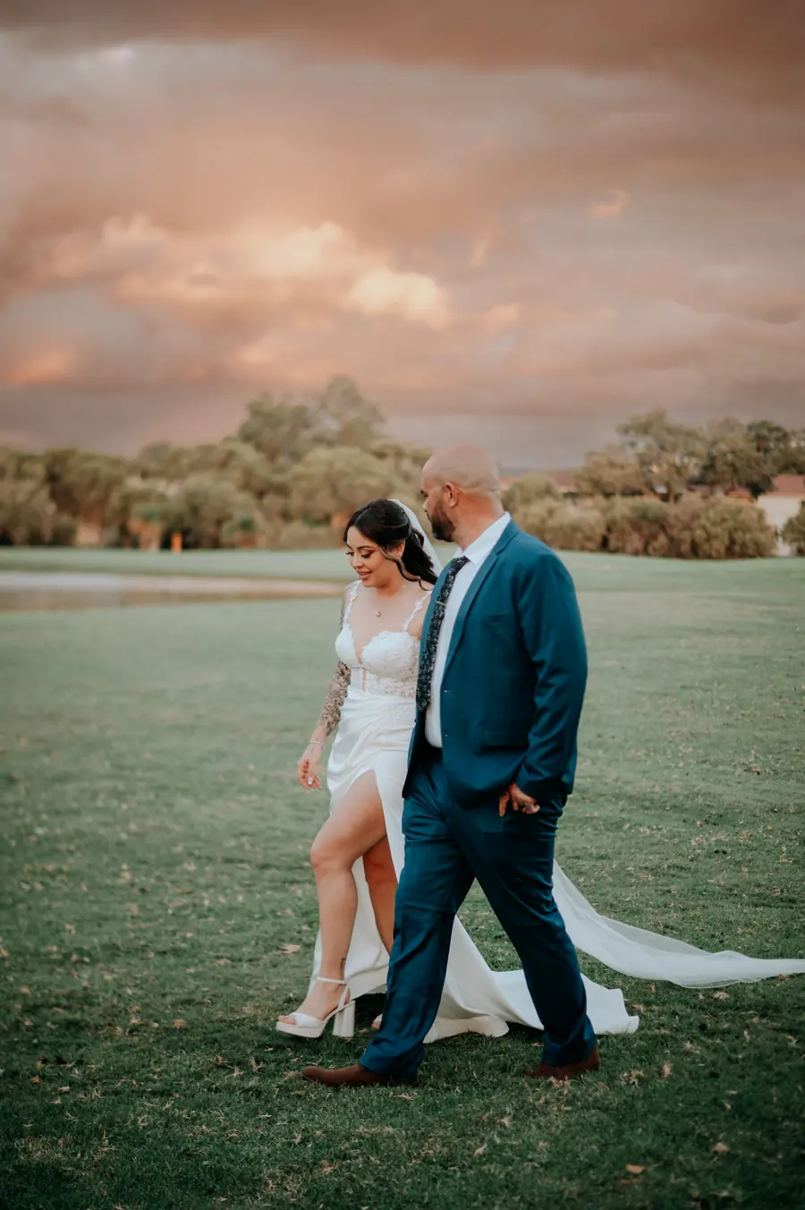 Kerry and Richard walking hand in hand at golden hour on the fairway