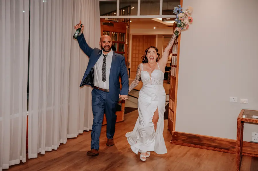 Kerry and Richard celebrating their reception entrance with a Heineken in hand