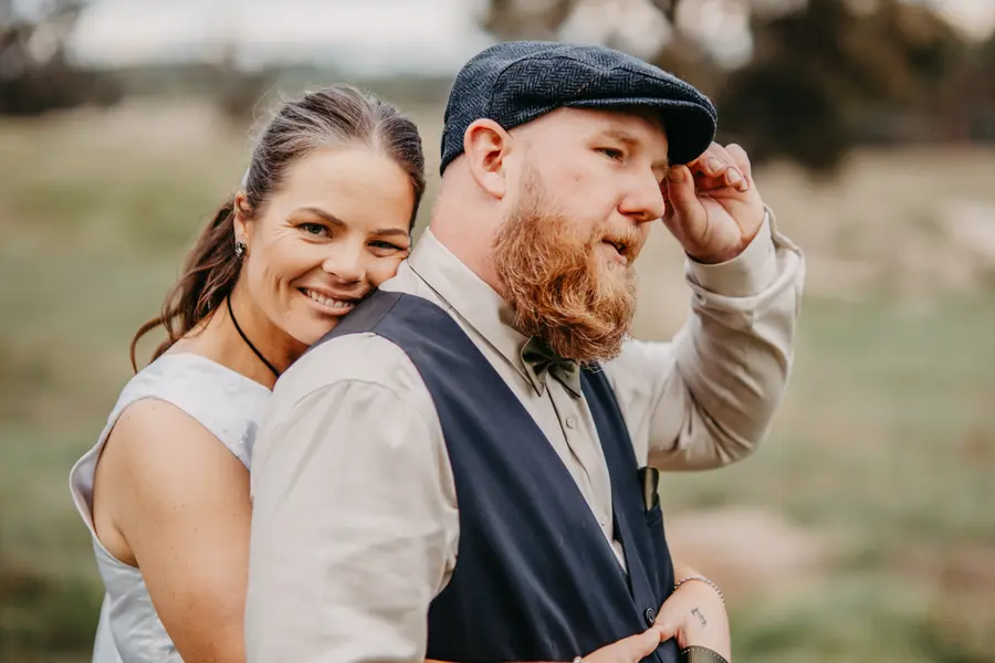 Liv and Ben laughing together beside a rusted vintage farm truck at Dalmore Farm, WA wheatbelt wedding
