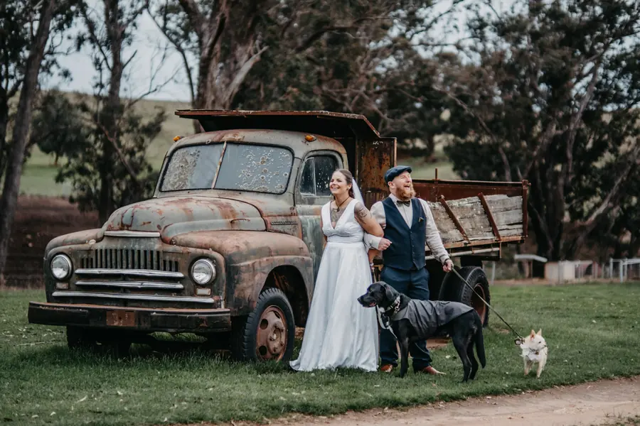 Liv and Ben with their two dogs beside an old truck at their rustic Dalmore Farm wedding