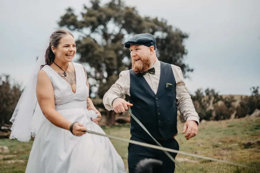 Ben in flat cap and waistcoat laughing with Liv during golden hour portraits at Dalmore Farm