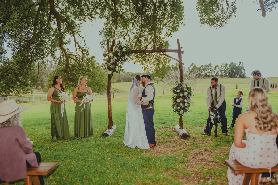 Liv and Ben's first kiss as a married couple under a tree arch at Dalmore Farm, with their dog looking on