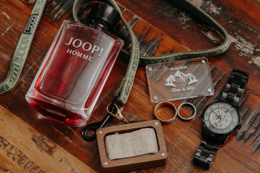 Groom's cologne, rings, watch and an engraved 'Ben & Liv' keepsake flat lay at Dalmore Farm