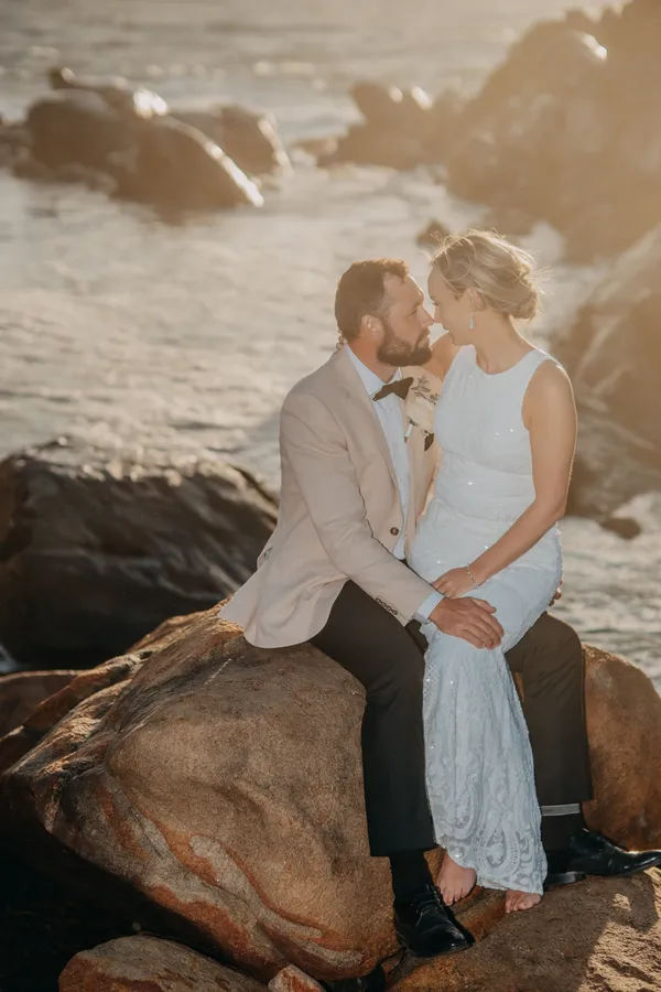 Victoria and Luck sitting close together on the rocks, golden hour light behind them