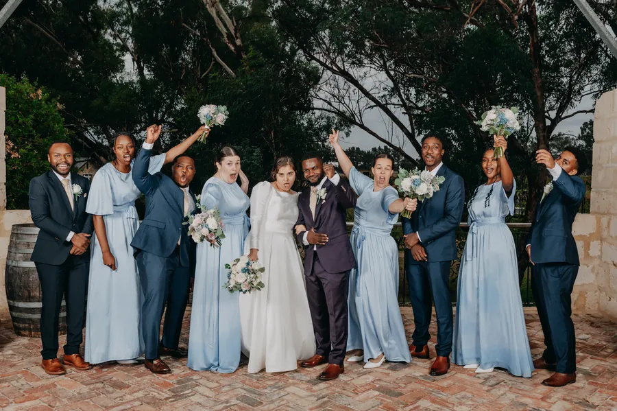 Bridesmaids and groomsmen cheering together at Chapel Farm Estate after the storm cleared