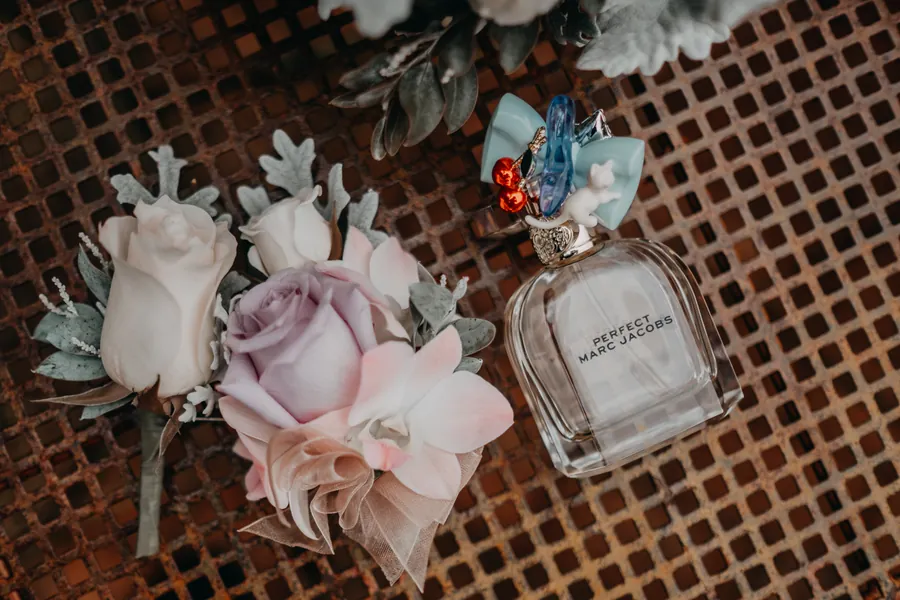 Flat-lay of the bridal bouquet, perfume and jewellery on a rustic wooden table