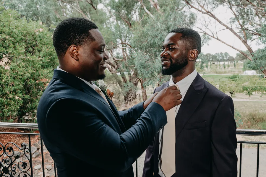 Jonathan having his tie straightened by a groomsman before the ceremony