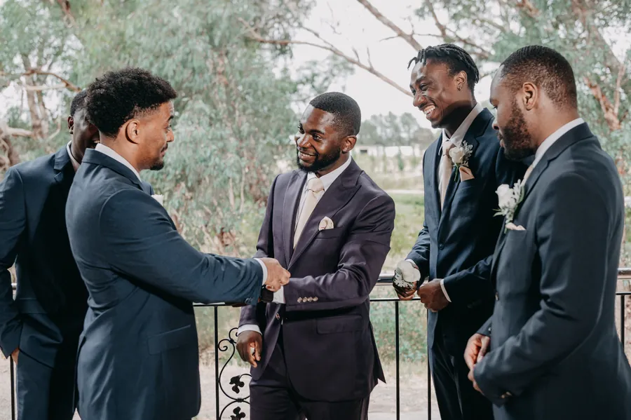 Jonathan and his groomsmen sharing a handshake on the balcony at Chapel Farm Estate