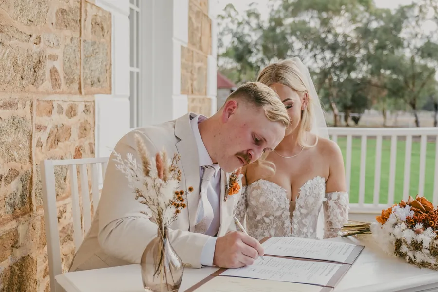 Close-up of Grace signing the marriage certificate at Buckland Estate