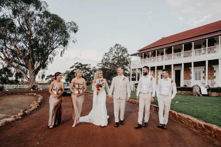 Grace and Lachie's wedding party walking together across the grounds at Buckland Estate