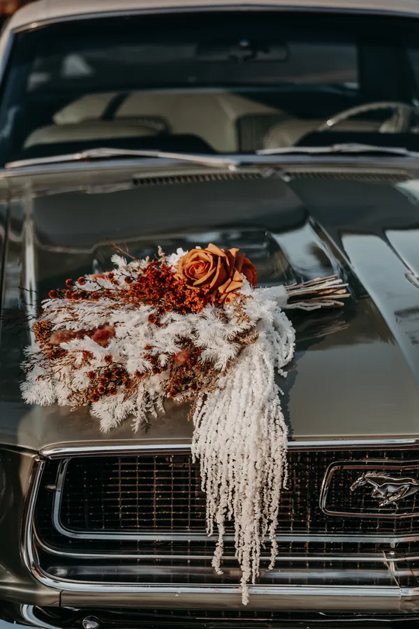 Dried floral wedding bouquet resting on the bonnet of the vintage car at Buckland Estate