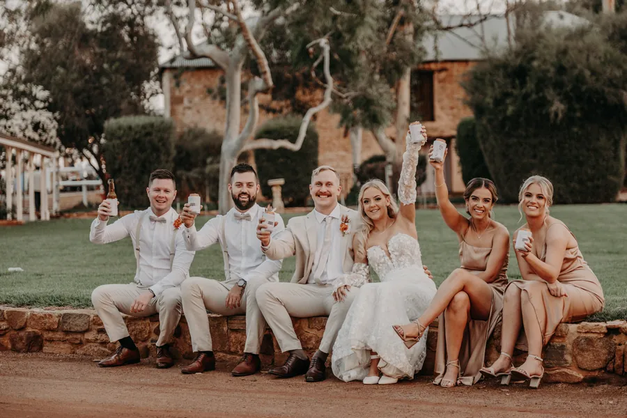 Grace and Lachie's wedding party cheering together on the lawn at Buckland Estate