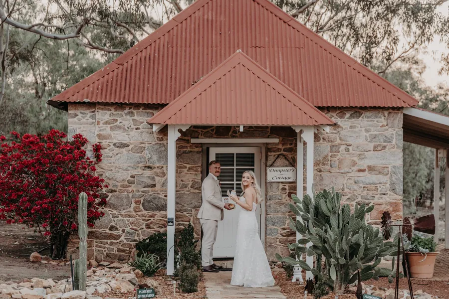 Grace and Lachie standing together in a timber doorway at the Buckland Estate homestead at dusk