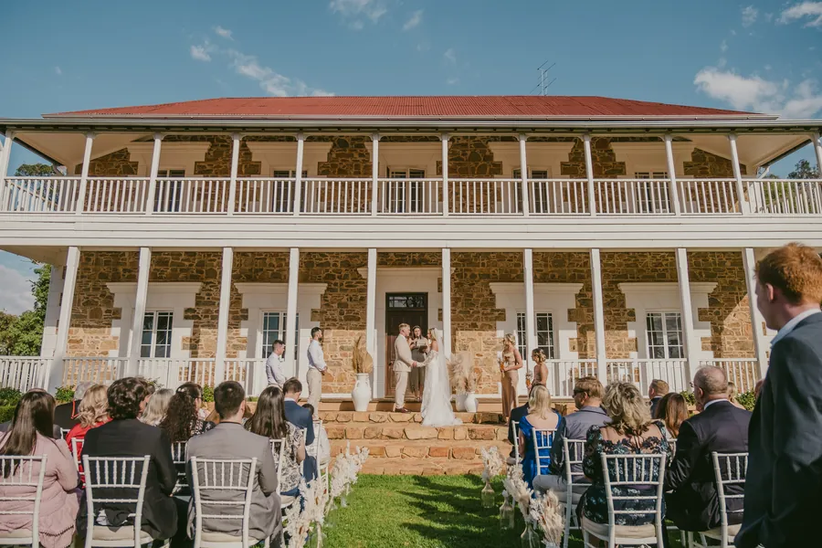 Wide symmetrical view of Buckland Estate's homestead with rows of white ceremony chairs set on the lawn