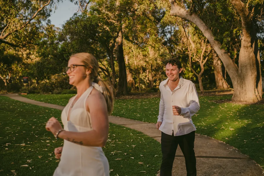 Kayla and Brett laughing together while walking along a Kings Park pathway at golden hour