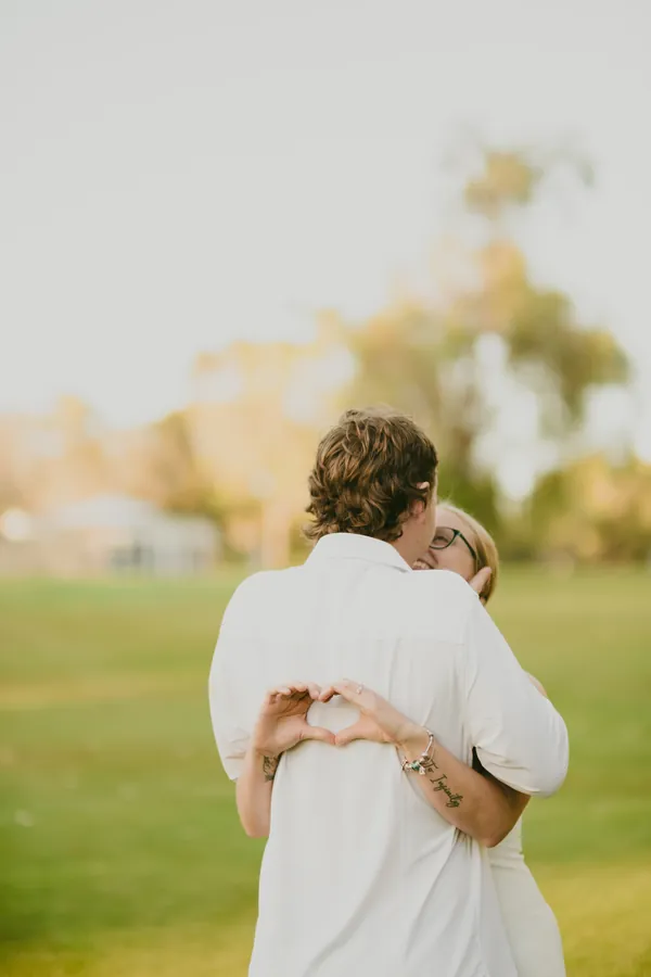 Kayla and Brett holding each other closely in a Kings Park field at golden hour