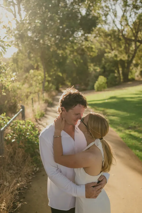 Kayla and Brett walking hand in hand along a Kings Park pathway at golden hour
