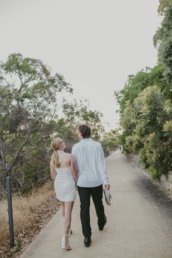 Kayla and Brett walking away down a tree-lined Kings Park pathway during their pre-wedding session