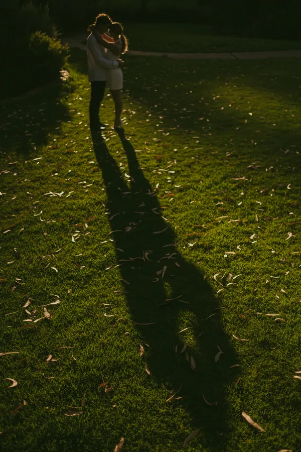 Silhouette of Kayla and Brett on the Kings Park lawn as the sun drops behind the trees