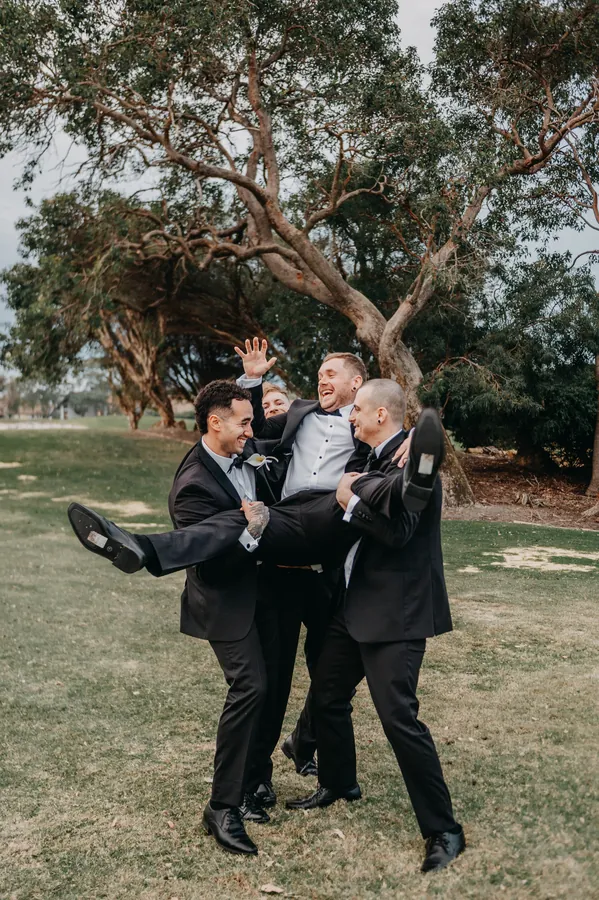 Groomsmen lifting a friend off the ground during portraits at The Vines Resort
