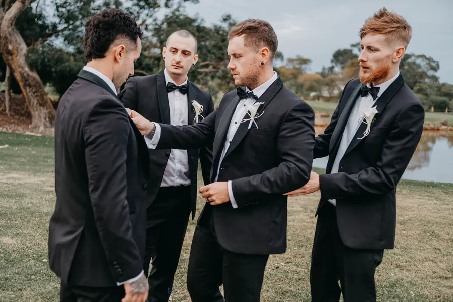 Groomsmen laughing while carrying each other across The Vines Resort grounds