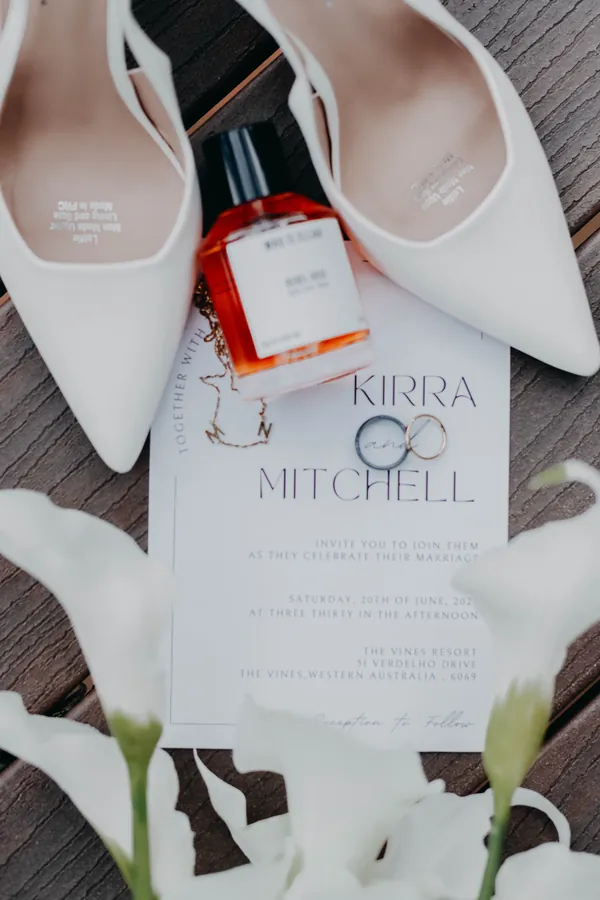 Kirra's wedding shoes and invitation suite styled with white florals at The Vines Resort