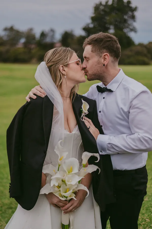 Kirra and Mitch sharing a relaxed kiss with Mitch's jacket over her shoulders