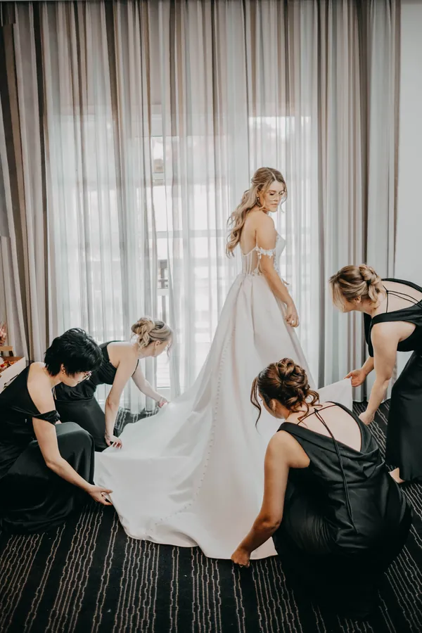 Bridesmaids helping arrange Kirra's dress train while getting ready at The Vines Resort